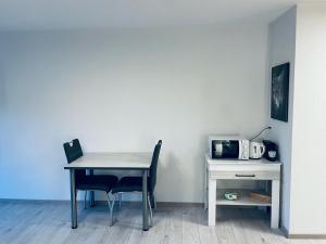 a table and chair next to a desk with a microwave at Studio de vacances aux Bains de Saillon in Saillon