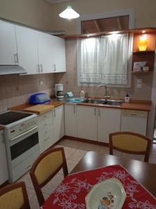 a kitchen with white cabinets and a table and a sink at Sofia's Garden in Nea Peramos