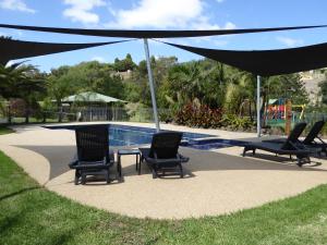 un grupo de sillas sentadas bajo una sombrilla junto a una piscina en Barwon Valley Lodge, en Geelong