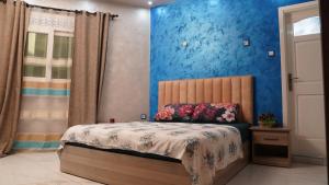 a bedroom with a bed with blue walls at Appartement luxe au centre ville in Annaba