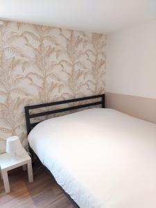 ein Schlafzimmer mit einem weißen Bett und einer Wand in der Unterkunft ° Studio 1 - Lunéville centre ° in Lunéville