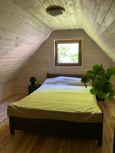 ein Schlafzimmer mit einem Bett im Dachgeschoss mit einem Fenster in der Unterkunft Domek przy Rozpadlisku in Podgórzyn