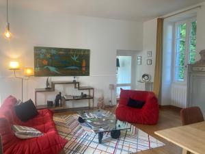 una sala de estar con 2 sillas rojas y una mesa. en Chambres d hôtes du Moulin à papier en Saint-Brieuc