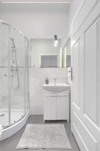 a white bathroom with a sink and a shower at Fair Point in Poznań