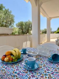 un tavolo con un piatto di frutta e tazze sopra di La Casa Degli Ulivi a Galatone