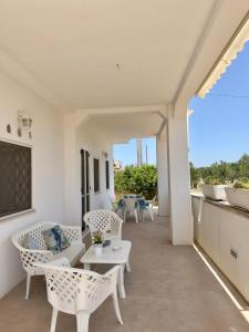 balcone con tavolo e sedie bianche. di La Casa Degli Ulivi a Galatone