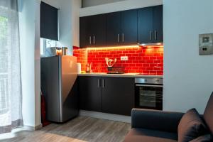 a kitchen with black cabinets and a red brick wall at Studio Apartment next to Alsos Ilision in Athens