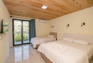 two beds in a room with a window at Beyoglu Pansiyon in Patara