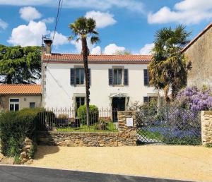 una casa blanca con una palmera y una valla en chambres d'hôtes maison de charme, en La Boissière-de-Montaigu