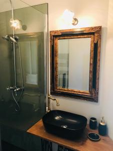baño con lavabo negro y espejo en chambres d'hôtes maison de charme, en La Boissière-de-Montaigu