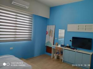 Habitación con pared azul, escritorio y TV. en WT BnB Taichung en Houli
