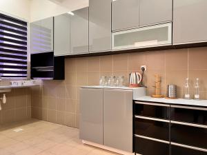 una cocina con electrodomésticos de acero inoxidable y armarios blancos en Ariesya Homestay, en Chemor