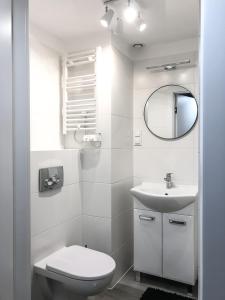 a white bathroom with a toilet and a sink at Airport Apartment in Wrocław