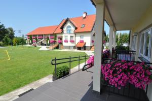 une maison avec un balcon orné de fleurs roses dans l'établissement Piaskowy Dom, à Jantar