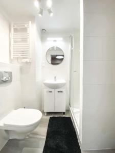 a white bathroom with a toilet and a sink at Airport Apartment in Wrocław