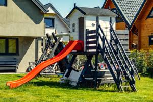 un parque infantil con un tobogán rojo en un patio en ZYGAdomki, en Gąski