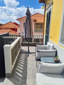 a patio with an umbrella on a balcony at Casas do Baleeiro - Whaler's Houses in Caniçal