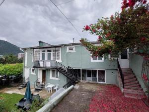 una casa verde con escaleras, mesa y sillas en Guest House Green Rose en Borjomi