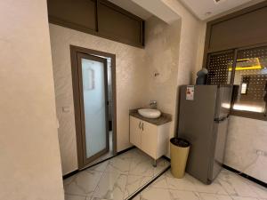 een kleine badkamer met een wastafel en een koelkast bij Belle résidence adrare tikouine agadir in Agadir