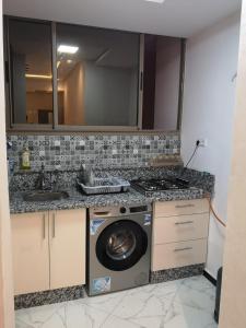 een keuken met een wasmachine en een wastafel bij Belle résidence adrare tikouine agadir in Agadir