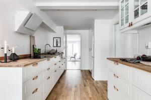 a kitchen with white cabinets and a wooden floor at Kullavik, 2 mil från Göteborg Villa Gläntan in Kullavik