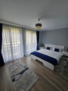 a bedroom with a large bed and large windows at Relax and Smile Rameț in Biceşti +75 photos
