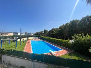 ein Schwimmbad in einem Garten neben einem Zaun in der Unterkunft Mya Vacanze in Torre dell'Orso