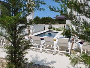 une terrasse avec des chaises blanches et une piscine dans l'établissement Villa Emperor, à Srima