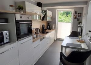 una cocina con armarios blancos y una mesa con sillas. en Am Quellenhäuschen, en Naila