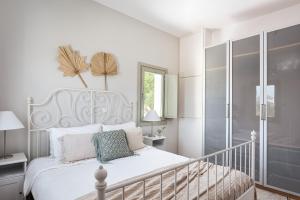 a white bedroom with a white bed and a balcony at Paros House Villa in Pounda