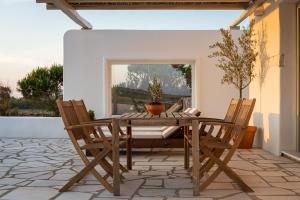 Paros House Villa في Pounda: طاولة وكراسي خشبية على الفناء