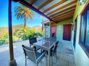 une terrasse avec une table, des chaises et un palmier dans l'établissement El Pirguan Holiday House, your oasis in La Gomera, à Vallehermoso