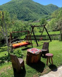 einen Spielplatz mit Schaukel und zwei Stühlen und Baumstumpf in der Unterkunft Seosko domaćinstvo Vidović in Banja Luka