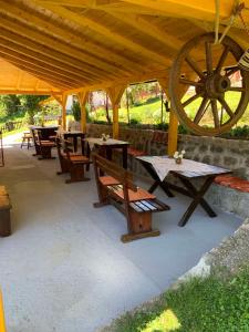 eine Gruppe von Tischen und Bänken unter einem Holzpavillon in der Unterkunft Seosko domaćinstvo Vidović in Banja Luka