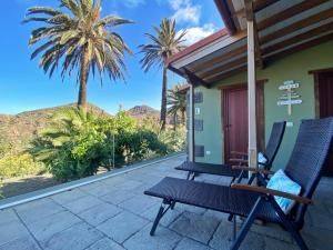 un patio con 2 sillas y palmeras en El Pirguan Holiday House, your oasis in La Gomera en Vallehermoso