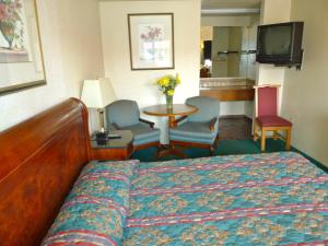 a hotel room with a bed and a table and chairs at Budget Inn Morgan Hill in Morgan Hill