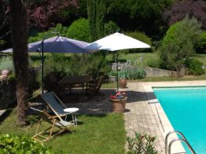 un patio con sombrilla, mesa y sillas junto a la piscina en Maison Epellius en Collonges-au-Mont-dʼOr