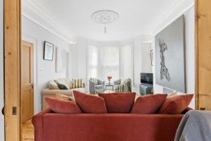 a living room with a red couch and a table at Hoe Park House, Central Victorian Townhouse Near Barbican and Seafront in Plymouth