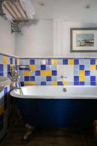 a bath tub in a bathroom with colorful tiles at The Griffin Inn in Fletching