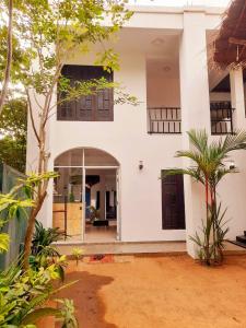 a white house with an open door and trees at Heritage Rangiri Villa in Dambulla