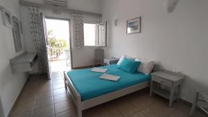 a bedroom with a bed with blue sheets and a window at Marianos Apartments in Antiparos