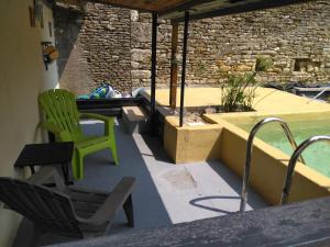 a patio with a green chair and a swimming pool at Gîte Zoé in Chervettes