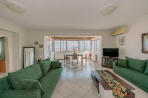 Una sala de estar con sofás verdes y una mesa. en AKANTHOS Rental House, en Kórinthos