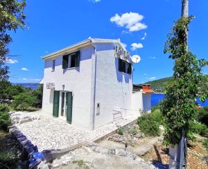 a small white house with green doors on a hill at Holiday Home Villa Marela in Drvenik Veli