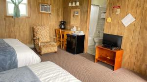 una camera d'albergo con letto, TV e sedia di Rachel's Motel and Cottages a Surrey