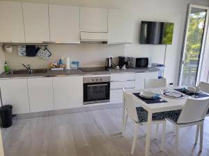 a kitchen with white cabinets and a table and chairs at Sogno di mare in Cavallino-Treporti +20 photos