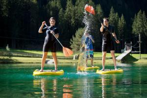 two people are on paddle boards in the water at Aparthotel Fuxbau in Flachau