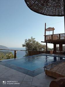 a swimming pool with a chair next to the ocean at 19th Century Neo-Modern KABAK VALLEY STONE HOUSE in Fethiye