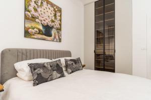 um quarto com uma cama branca com almofadas e um quadro em Agrippas St 8 - Isrentals em Jerusalém