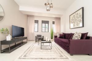 sala de estar con sofá púrpura y TV en Agrippas St 8 - Isrentals en Jerusalén